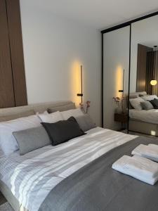 a large white bed in a room with a mirror at Casella Apartment E34 Let's Sea Baltic Park in Gąski +53 photos