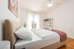 a white bedroom with a bed and a window at Laguna Apartments in Pag