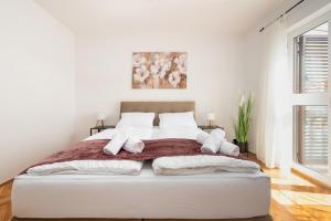 a white bedroom with a bed with towels on it at Laguna Apartments in Pag