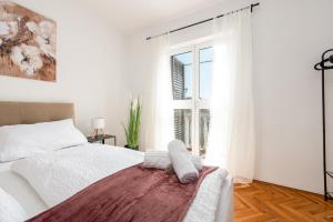 a white bedroom with a bed and a window at Laguna Apartments in Pag
