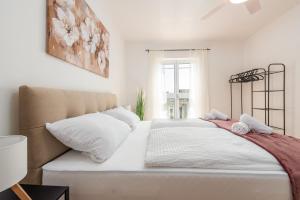 a white bedroom with a large bed with white pillows at Laguna Apartments in Pag