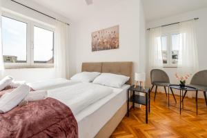 a white bedroom with two beds and a table at Laguna Apartments in Pag +34 photos
