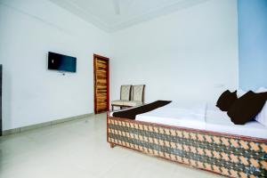 a bedroom with a bed with a tv and a chair at Hotel O KLER Guest House in Kharar +35 photos