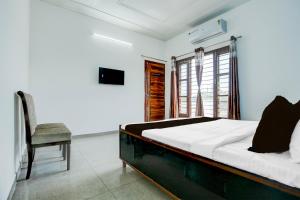 a bedroom with a bed and a chair and a window at Hotel O KLER Guest House in Kharar