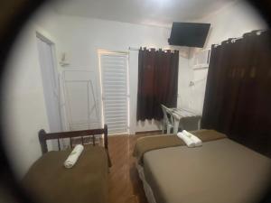 a small bedroom with two beds and a television at Vale do Pontal Angra Suites in Angra dos Reis