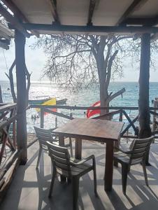 a wooden table and chairs with the ocean in the background at Pikua Beach Baru in Playa Blanca