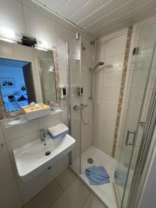 a bathroom with a glass shower and a sink at Hotel Zum Hanseaten in Borkum +24 photos