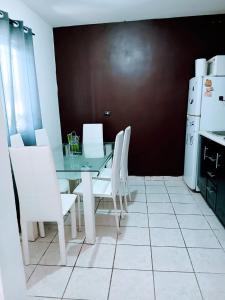 a dining room with a glass table and white chairs at Tu hogar ideal, cómodo, acogedor y único in Los Mochis