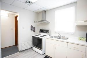 a white kitchen with a stove and a sink at Wardens Quarters: 2 Bedroom Apt in Sault Ste. Marie