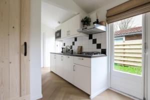 a white kitchen with a stove and a window at Rekerlanden 270 in Warmenhuizen
