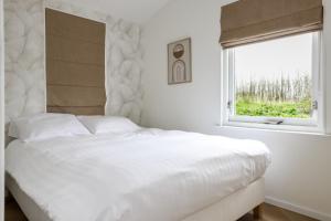 a white bedroom with a large bed and a window at Rekerlanden 270 in Warmenhuizen
