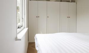 a white bedroom with a bed and a window at Rekerlanden 270 in Warmenhuizen
