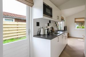a kitchen with white cabinets and a large window at Rekerlanden 270 in Warmenhuizen