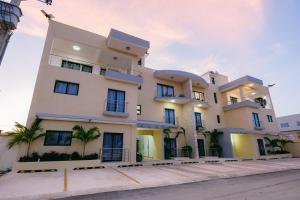 a large white building with palm trees in front of it at Arena Aparta Hotel in Punta Cana