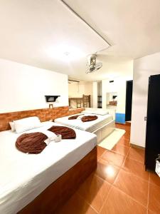 two beds in a large room with white walls at Hotel Sol y Luna 1 in Medellín