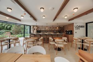 a restaurant with wooden tables and white chairs at Lomm By Somos The Group in Medellín
