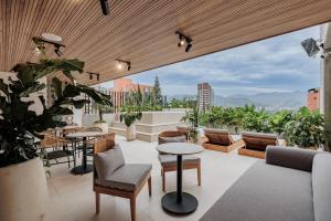 a rooftop patio with tables and chairs and plants at Lomm By Somos The Group in Medellín