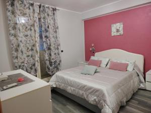 a bedroom with a bed and a pink wall at Sweet Home in Oliveri