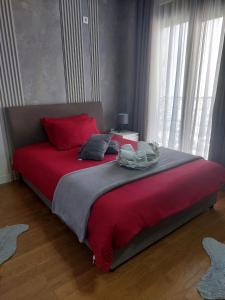 a bedroom with a large red bed with red pillows at Aria Apartmani in Podgorica