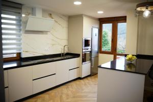 a kitchen with white cabinets and black counter tops at La CASA ROJA SOLARES in Solares