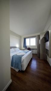 a bedroom with a large bed and a television at LH Plaza Hotel in Chapecó