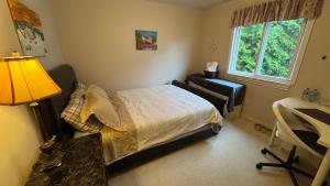 a bedroom with a bed and a desk and a lamp at Warm house3 in Coquitlam