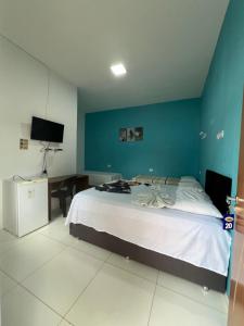 a bedroom with a large bed with a blue wall at Pousada Paraiso in Canudos