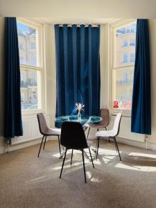 a table and chairs in a room with blue curtains at First Avenue Apartments Stylish 2 & 3 Bed Flats in Central Hove in Brighton & Hove +25 photos