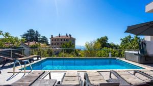 a swimming pool with chairs and an umbrella at Villa Angello in Matulji