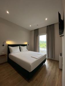 a bedroom with a large white bed and a window at Merly Hotel in Përmet