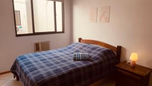 a bedroom with a bed with a blue plaid blanket at Aconchego - com Garagem in Santa Maria