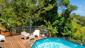 a deck with a jacuzzi tub and chairs at Douceur de Fèves - T2 de Charme avec Piscine et vue mer à la Trinité in La Trinité