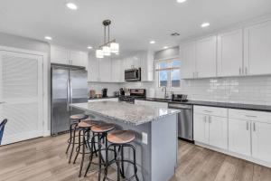a kitchen with white cabinets and a island with bar stools at Prof Cleaned | Fast WiFi | BBQ | Linen & Towels in Seaside Heights