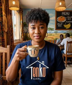 a young boy holding a cup of coffee at Village Tenko in Ouagadougou