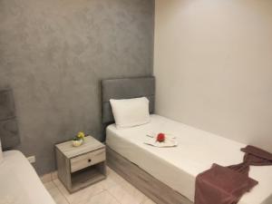 a small bedroom with a white bed and a table at Sone Al Boos in Cairo +2 photos