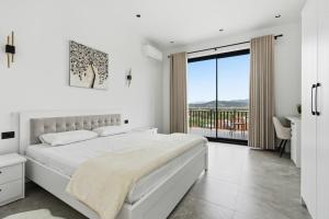 a white bedroom with a large bed and a balcony at Vila Palma in Berat +52 photos
