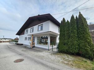 ein weißes Haus mit schwarzem Dach in einer Straße in der Unterkunft Bachblick Apartment in Kremsmünster