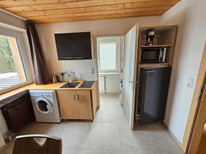 eine kleine Küche mit Spüle sowie Waschmaschine und Trockner in der Unterkunft Bachblick Apartment in Kremsmünster