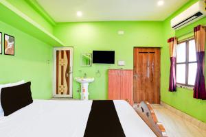 a green bedroom with a bed and a sink at Capital O Sri Krishna Palace Near Sum Hospital in Durgāpur