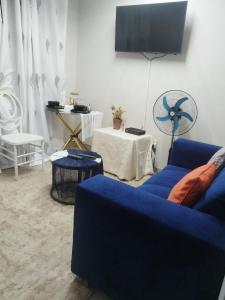 a living room with a blue couch and a fan at Soshanguve Lux Accom Room 02 in Soshanguve