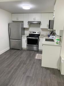 a kitchen with stainless steel appliances and white cabinets at Gladwin one bedroom in Abbotsford