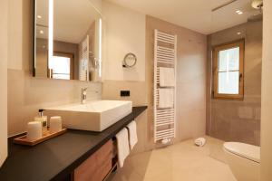 a bathroom with a white sink and a toilet at Landhotel Haringerhof mit Saunawelt und Naturbadeteich in Grafenhausen