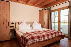 a bedroom with a bed with a red and white blanket at Landhotel Haringerhof mit Saunawelt und Naturbadeteich in Grafenhausen