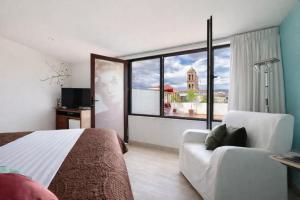 a bedroom with a bed and a couch and a window at El Sueño Hotel & Spa in Puebla