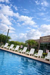Eine Reihe weißer Stühle neben einem Schwimmbecken in der Unterkunft Hotel Fiesta Brava Inn Río Bravo in Primero de Mayo