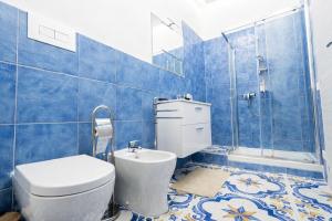 a blue tiled bathroom with a toilet and a shower at Fantasy House Suites in Forio d'Ischia +64 photos