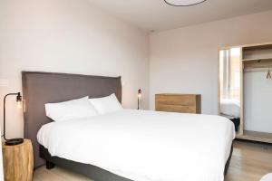 a bedroom with a large white bed and a window at Skyline Flats Gent in Ghent