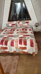 a bed with a quilt on it in front of a window at Cabana Magia Apusenilor in Arada
