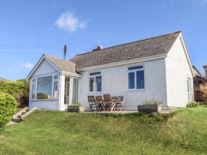 a white house with chairs on a lawn at Highdown in Bigbury on Sea