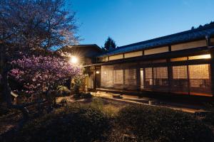 a house with a flowering tree in front of it at Tokyo Sake House in Ome